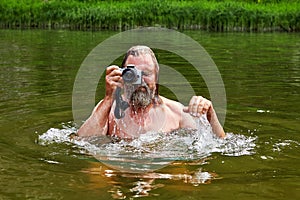 Wet man takes photos in river