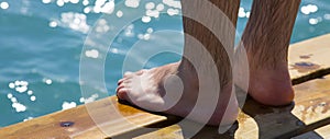 Wet men`s feet on the sea pier