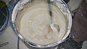 Wet mortar cement paste, mixed in bucket at house construction site, closeup detail from above