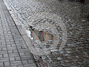 Wet paved gray paving road with puddles on the street