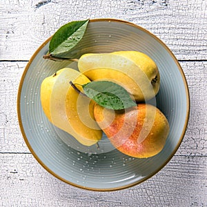 Wet pears with leaves on blue plate