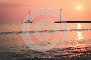 Wet pebble stones and sailing boat at morning seaside