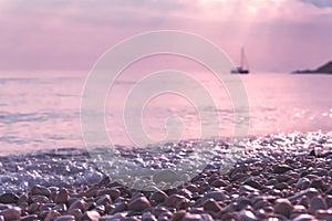 Wet pebble stones and sailing boat at morning seaside