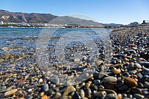 Wet pebbles on the beach of Gelendzhik in the foreground, large. Then we see The Gelendzhik Bay and the Caucasus mountains.