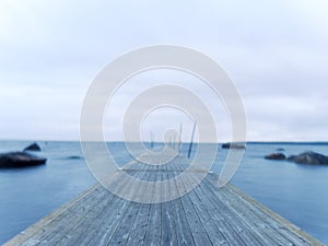 Wet pier in smooth water of sea bay. Mole anchored with steel poles into bottom