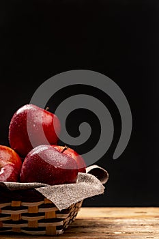 Wet red apples in bowl on darkness