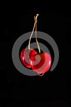 Wet red cherries on the black isolated background