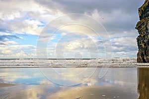 Wet sand and cliff reflections