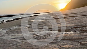 Wet sand on wild beach at ocean shore at sunset. Golden hour and white sand on tropical seaside. Sea shore background in