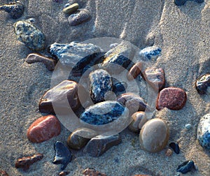 Wet sea pebble stones in the sand