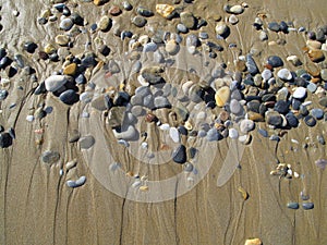 Wet sea pebbles on the sand