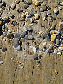 Wet sea pebbles on the wet sand