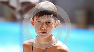 Wet serious boy after a swimming pool looks at the camera