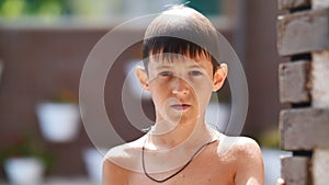 Wet serious boy after a swimming pool looks at the camera, close-up