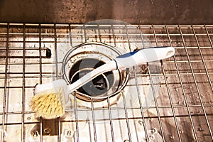 Wet stainless steel sink with garbage disposal and wire rack with scrub brush laying on it