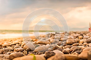 Wet stones summer beach closeup with sea, mountain and sky background