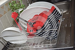 Wet striped umbrella is drying in a dish rack.