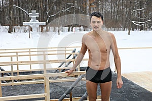 A wet undressed man stands near a hole in the photo