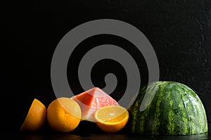 Wet Watermelon and Oranges Halves on Black Background