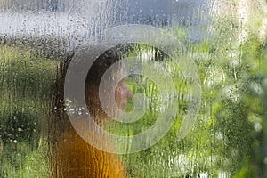 Wet window glass with blurred woman silhouette