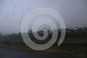 a wet windshield on the side of a road with rain droplets in the air