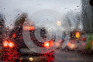 Wet windshield water flows blurred car lights