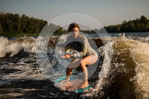 wet woman wakesurfer skilfully riding on splashing wave on a warm day