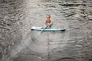 Wet woman in the water holding tight rope and board for wake nearby