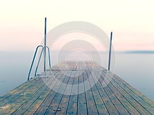 Wet pier in smooth water of sea bay. Mole anchored with steel poles into bottom