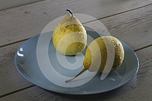 Wet yellow golden pears on a blue plate