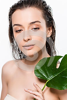 Wet young woman with green palm leaf with water drops isolated on white