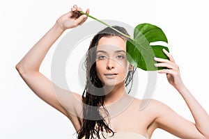 Wet young woman posing with green palm leaf with water drops isolated on white