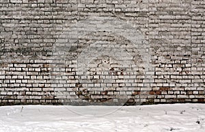 Wethered brick wall and pile of snow.