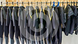 Wetsuits hanging on a rack.