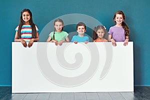 Weve got a message for you. Studio portrait of a diverse group of kids standing behind a large blank banner against a