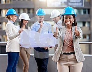 Weve got this plan going. a young female architect showing a thumbs up while working with coworkers against a city