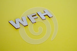 WFH wooden letters representing Work From Home on yellow background