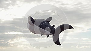 Whale shark kite flying in cloudy sky at sunny day. Holiday festival event on beach