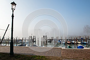 Wharf in quit bay, foggy weather, italian island Burano, province of Venice, Italy. Little beautiful dock with boats,