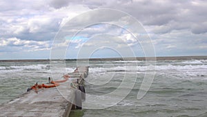 Wharf and strong waves, bad weather, gray clouds, storm on the sea