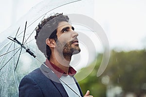 What a beautiful day. Cropped shot of a handsome young businessman on his morning commute in the rain.