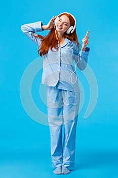 What beautiful morning to listen favorite playlist. Vertical full-length portrait tender redhead woman in pyjama