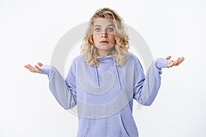 What do I know. Portrait of confused and unaware cute european blond woman with blue eyes standing questioned with