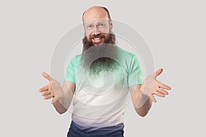 What do you need? Portrait of angry middle aged bald man with long beard in light green t-shirt standing, looking at camera with
