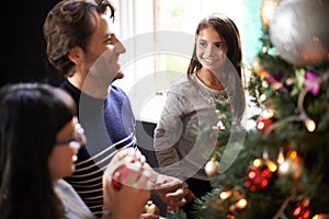 What do you think dad. a family placing ornaments on christmas tree.