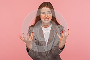 What do you want from me? Portrait of young mad woman in business suit raising hands and looking with anger hate