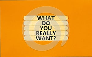 What do you really want symbol. Concept words What do you really want on wooden stick. Beautiful orange table orange background.