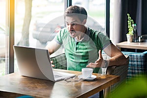 Čo robiť vy chcieť? mladý podnikateľ v zelený pracovné hľadá a jačiace na prenosný počítač obrazovka na volanie 