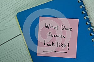 What Does Success Look Like? write on sticky notes isolated on Wooden Table photo