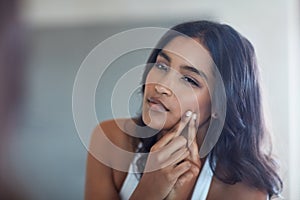 What does your skin say about you. a young woman squeezing a pimple in front of the bathroom mirror.